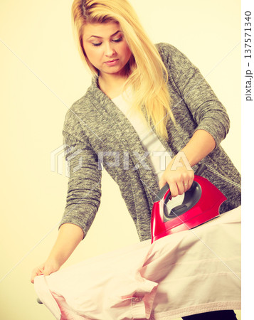 Woman holding iron about to do ironing Woman holding iron about to do ironing 137571340