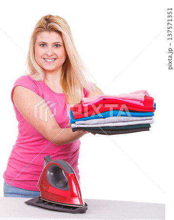 Woman holding folded clothes after ironing 137571351