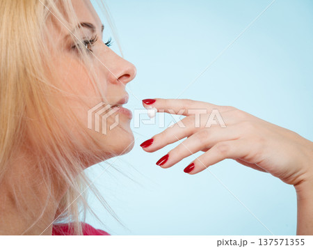 Woman applies lip balm cream to her lips Woman applies lip balm cream to her lips 137571355