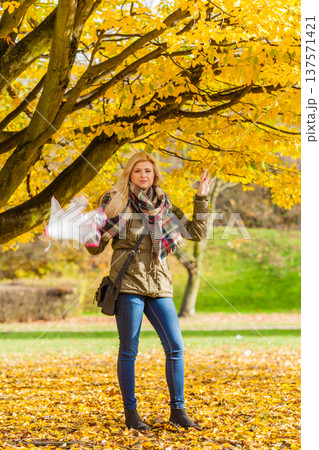Woman walking in park with umbrella Woman walking in park with umbrella 137571421
