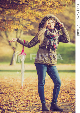 Woman walking in park with umbrella Woman walking in park with umbrella 137571423