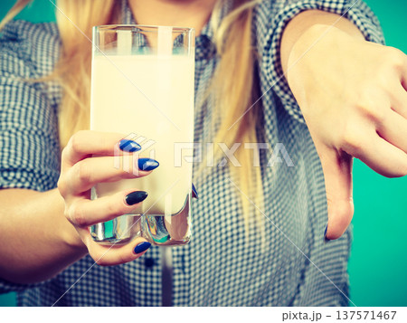 Woman holding milk glass showing thumb down 137571467
