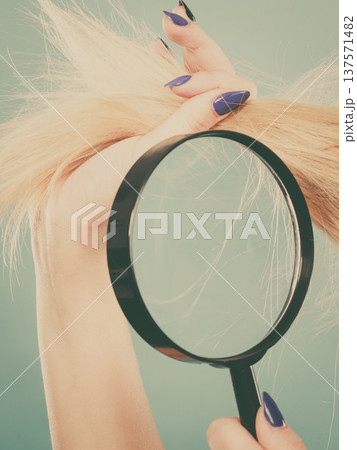 Woman looking at hair through magnifying glass 137571482