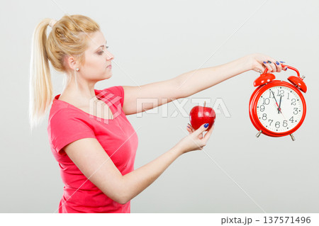 Happy woman holding clock, apple and measuring tape Happy woman holding clock, apple and measuring tape 137571496