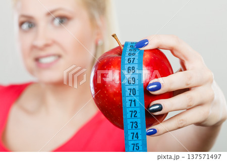 Happy woman holding apple and measuring tape Happy woman holding apple and measuring tape 137571497