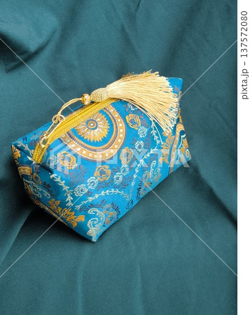 Blue jacquard cosmetic bag on green draped fabric in oriental style Blue jacquard cosmetic bag on green draped fabric in oriental style 137572080