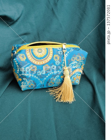 Blue jacquard cosmetic bag on green draped fabric in oriental style 137572081
