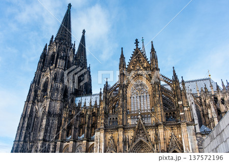 Cologne Cathedral in Germany features intricate Gothic architecture with tall spires and detailed stonework against a blue sky. 137572196