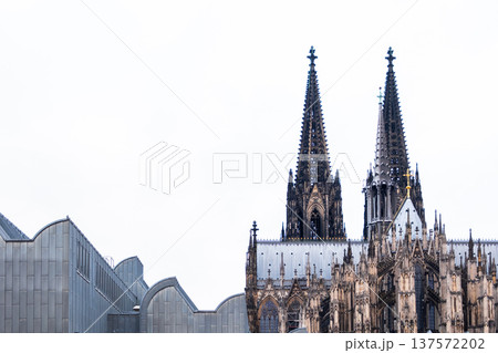 Cologne Cathedral in Germany features intricate Gothic architecture with tall spires and detailed stonework against a blue sky. Cologne Cathedral in Germany features intricate Gothic architecture with tall spires and detailed stonework against a blue sky. 137572202