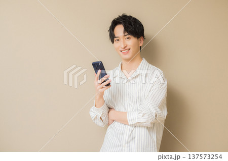スマホを見る若い男性　 137573254