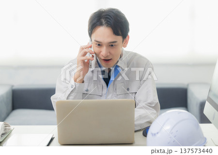 会社でクレーム対応する作業着の男性 137573440