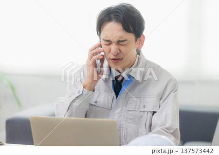会社でクレーム対応する作業着の男性 137573442