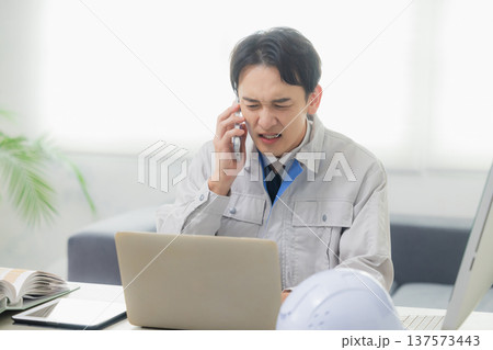 会社でクレーム対応する作業着の男性 137573443