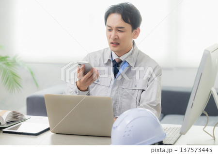 会社でクレーム対応する作業着の男性 137573445