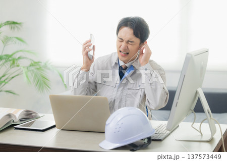 会社でクレーム対応する作業着の男性 137573449
