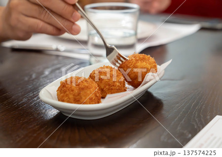 Golden crispy fried snack balls served on a small ceramic plate in a restaurant setting showing crunchy texture and warm freshly cooked comfort food ready to eat. 137574225