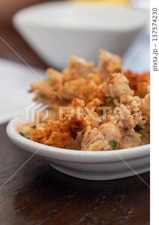 Crispy fried squid tentacles served on a plate with a lemon wedge in a restaurant setting, a golden seafood appetizer with crunchy texture and savory flavor. 137574230