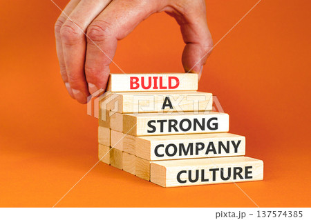 Strong company culture symbol. Concept words Build a strong company culture on beautiful wooden blocks. Beautiful orange paper background. Business strong company culture concept. Copy space. Strong company culture symbol. Concept words Build a strong company culture on beautiful wooden blocks. Beautiful orange paper background. Business strong company culture concept. Copy space. 137574385
