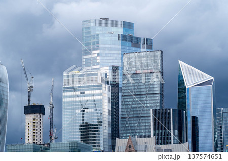 Modern glass skyscrapers in the London financial district rise across the River Thames representing contemporary urban architecture and a dynamic business city skyline. 137574651