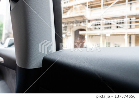 Close view of black leather door panel and window frame inside a modern vehicle emphasizing automotive interior materials and design details. Close view of black leather door panel and window frame inside a modern vehicle emphasizing automotive interior materials and design details. 137574656
