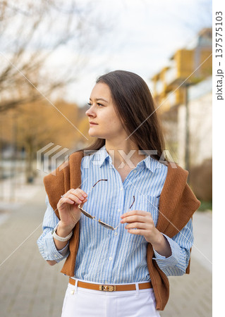 Elegant young woman in old money style holding sunglasses while standing on pier near Prague in early spring. Quiet luxury aesthetic and refined European elegance concept. Elegant young woman in old money style holding sunglasses while standing on pier near Prague in early spring. Quiet luxury aesthetic and refined European elegance concept. 137575103