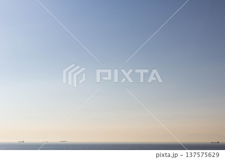 穏やかな海の夕景と遠くに見える貨物船 コピースペース 137575629