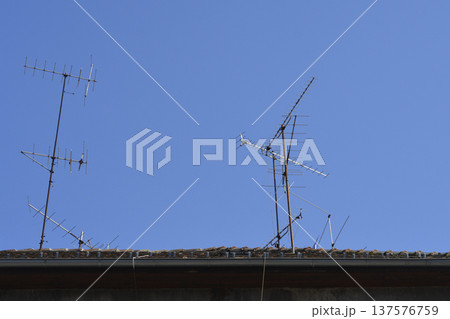 Television antennas on a house roof against blue sky 137576759