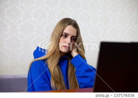 Young blonde woman rubs painful neck while working on laptop. She suffers from poor posture and ergonomic issues at home office. Health problem concept Young blonde woman rubs painful neck while working on laptop. She suffers from poor posture and ergonomic issues at home office. Health problem concept 137576836