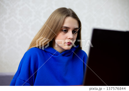 Young professional woman focuses on laptop screen during video call. She maintains eye contact with remote colleague or client. Online meeting and corporate communication concept Young professional woman focuses on laptop screen during video call. She maintains eye contact with remote colleague or client. Online meeting and corporate communication concept 137576844