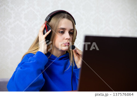 Young female streamer wears gaming headset and holds microphone close to face. She checks equipment before starting live broadcast online. Gamer girl prepares for stream at home Young female streamer wears gaming headset and holds microphone close to face. She checks equipment before starting live broadcast online. Gamer girl prepares for stream at home 137576864