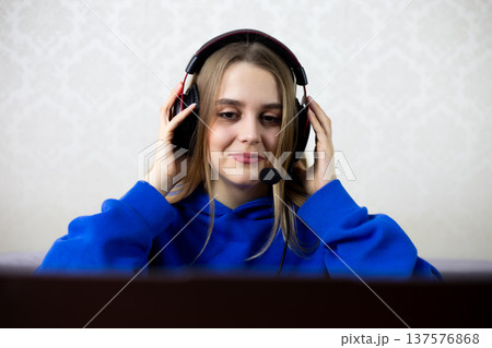 Young woman smiles serenely while listening to therapy session or affirmations on headset, practices self-care and mental wellness through audio guidance at home. Healing and mindfulness concept 137576868