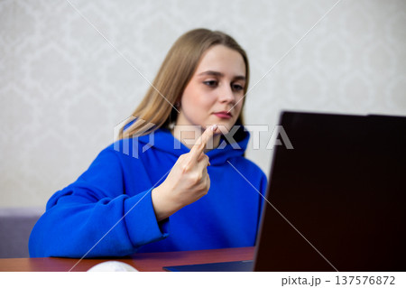 Happy young woman points index finger at laptop screen celebrating first place ranking. She learns her favorite project or company achieved top spot. Success and victory concept at home 137576872