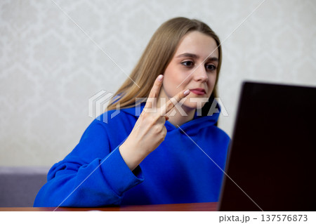 Excited football fan celebrates second goal with two fingers raised toward laptop. She cheers loudly as her team scores again during live match. Joyful reaction at home Excited football fan celebrates second goal with two fingers raised toward laptop. She cheers loudly as her team scores again during live match. Joyful reaction at home 137576873