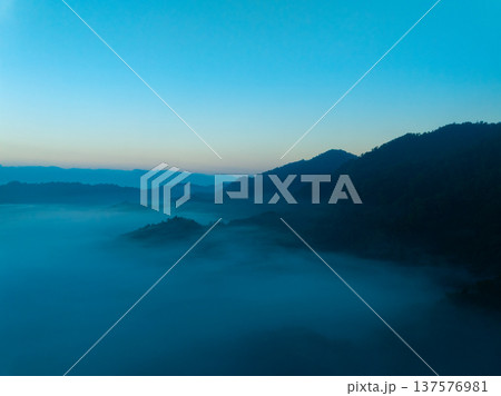 Aerial view of flowing fog waves on mountain tropical rainforest,Bird eye view image over the clouds Amazing nature background with clouds and mountain peaks in Thailand Aerial view of flowing fog waves on mountain tropical rainforest,Bird eye view image over the clouds Amazing nature background with clouds and mountain peaks in Thailand 137576981