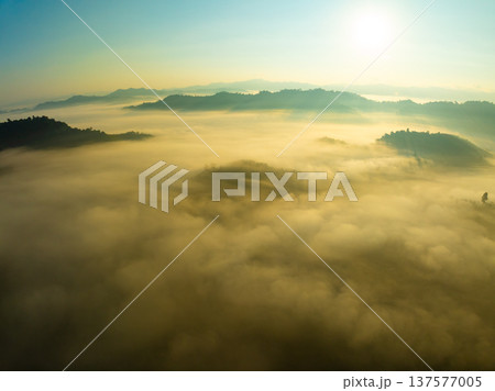 Aerial view of flowing fog waves on mountain tropical rainforest,Bird eye view image over the clouds Amazing nature background with clouds and mountain peaks in Thailand 137577005