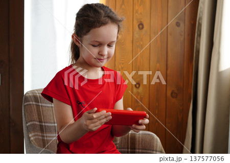Little Girl Using Smartphone While Sitting In Chair 137577056