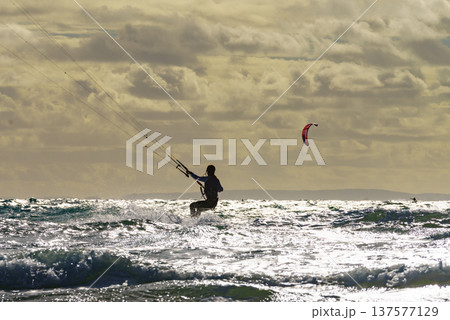 Kite surfer riding waves. Kiteboarding sport. 137577129