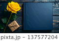 父の日のプレゼント、黄色いバラとアルバム(手帳型)。黒い木目調の背景。 137577204