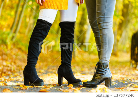 Two women wearing autumn black boots shoes Two women wearing autumn black boots shoes 137577240