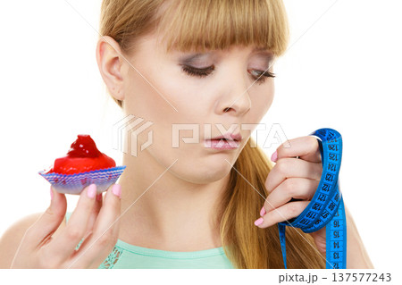 Woman holds cupcake trying to resist temptation 137577243