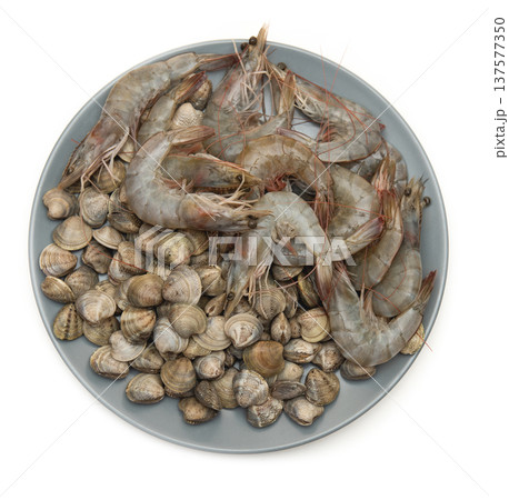 raw shrimp and seashells on grey plate and white background 137577350