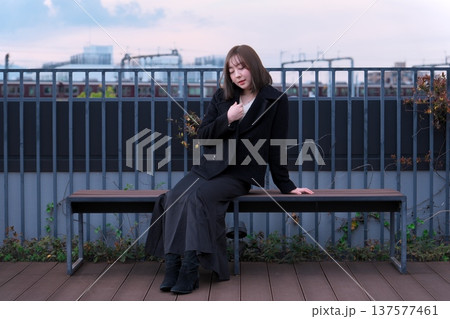 都会のテラスで佇む女性と阪急電鉄の線路。大阪の都市インフラと冬のライフスタイルが交差する風景。 都会のテラスで佇む女性と阪急電鉄の線路。大阪の都市インフラと冬のライフスタイルが交差する風景。 137577461