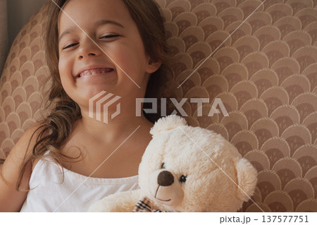 Genuine happiness: a smiling girl embraces her teddy bear with overwhelming affection 137577751