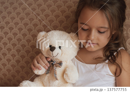 Serious guardianship: a determined girl holds her teddy bear with a concentrated expression 137577755