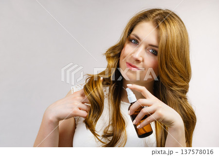 Woman applying hair cosmetic Woman applying hair cosmetic 137578016