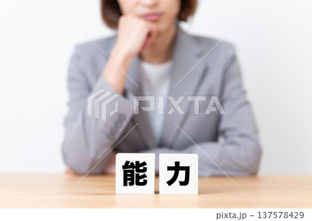 能力のブロックと悩むスーツ姿のミドル女性 能力のブロックと悩むスーツ姿のミドル女性 137578429