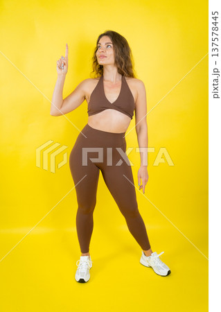 Woman in activewear pointing finger up for direction Woman in activewear pointing finger up for direction 137578445