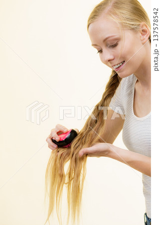 Blonde girl with long braid hair holds brush 137578542