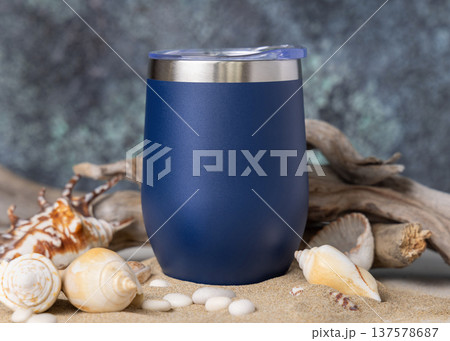 Wine tumbler mockup, blank blue stainless steel cup on sand with seashells and driftwood,  copy space. 137578687