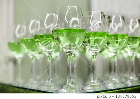 Row of wine glasses filled with vibrant green liquid Row of wine glasses filled with vibrant green liquid 137579358